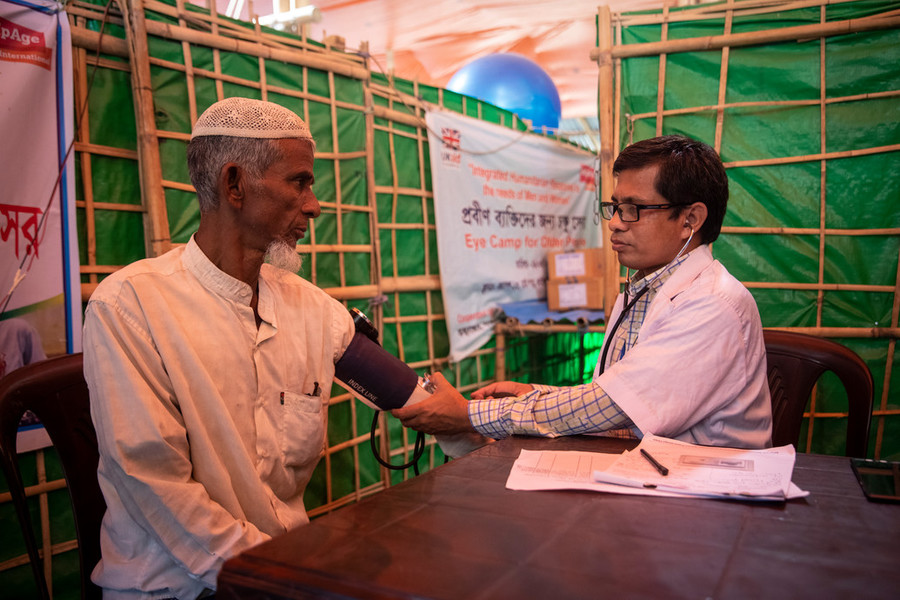 an older Rohingya man gets his blood pressure checked by a doctor at a refugee camp in Bangladesh.