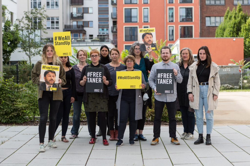 A group of activists hold up banners reading, free Taner.