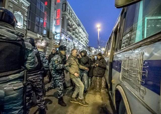 A group of police restrain a man and load him into a police vehicle